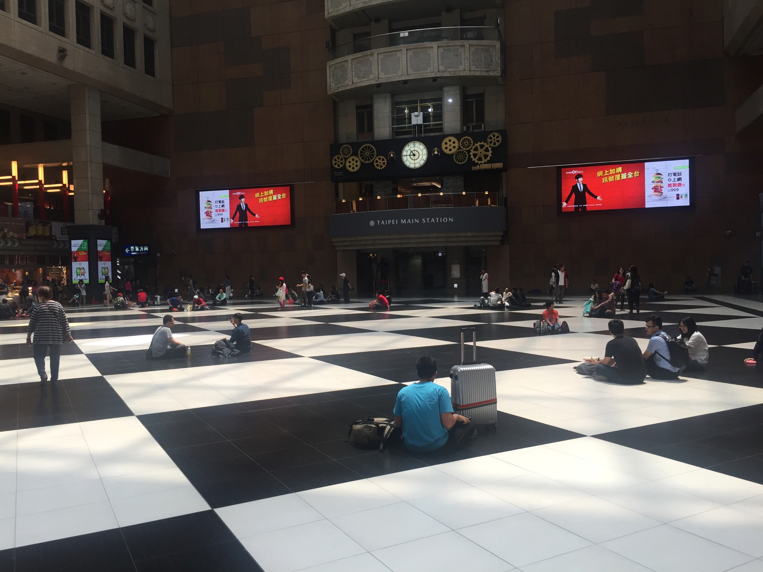 people sitting on the floor inside Taipei Main Station