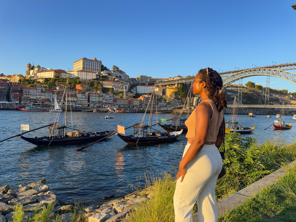 Solo traveler watching sunset from the Vila Nova de Gaia waterfront with views of Porto Portugal across the Douro river