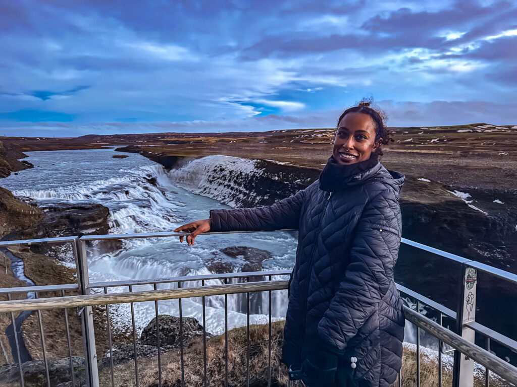 woman standing in front of godafoss waterfall in iceland