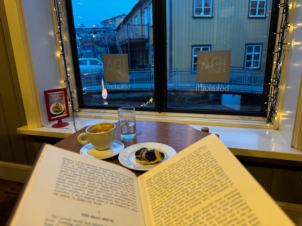 book with coffee and croissant with the view out of the window in reykjavik iceland