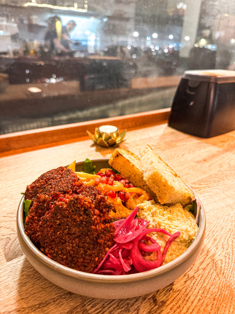 A fresh Mediterranean-style takeaway bowl from Chickpea in Reykjavik featuring roasted cauliflower, falafel, and pomegranate seeds.