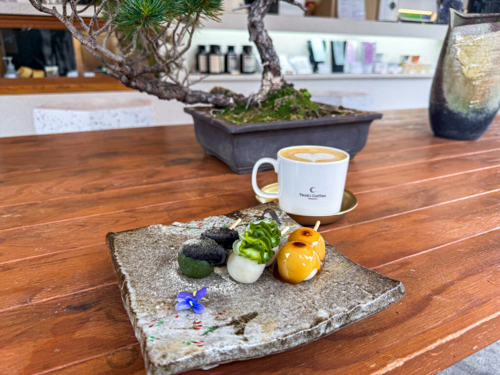 A set of three distinct odango rice cakes served alongside a hot latte at Tsuki Coffee in Yamadera, Japan.