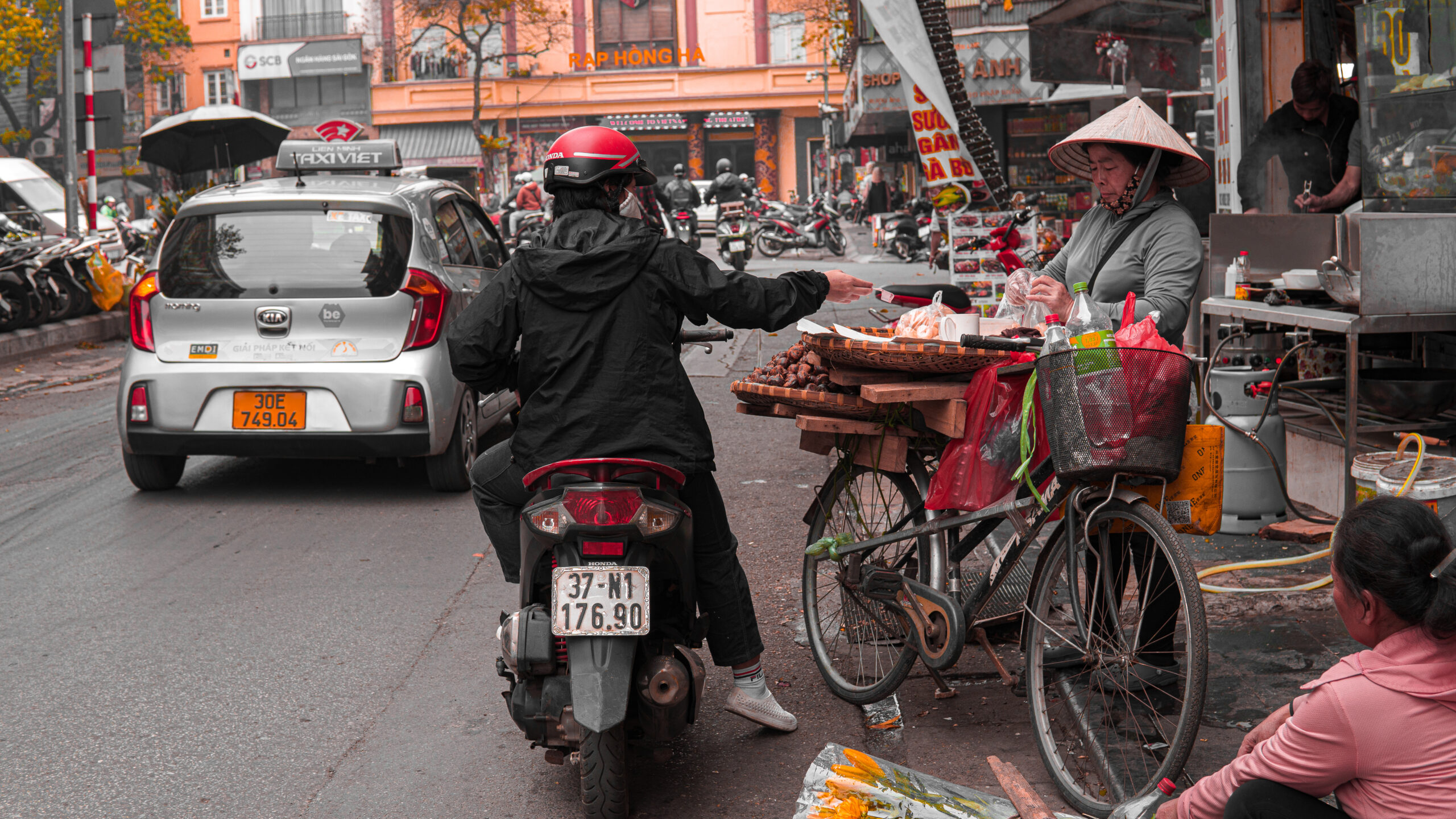 man on motorcycle and local vietnamese woman selling fruit on the bustling streets of hanoi, vietnam